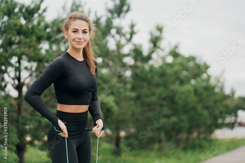 portrait of a woman of Caucasian appearance in black tight sports comfortable clothing. time the morning. Sports with a skipping rope stretching, Healthy lifestyle.
