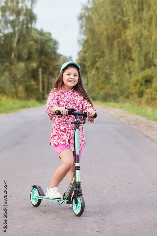 happy little girl riding scooter on country road happy little girl riding scooter on country road