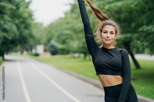 portrait of a happy brunette woman of European appearance, posing for the camera, holding her hair in her hands and smiling. nice weather summer day