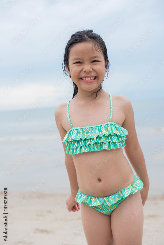 Little girl playing on the beach on summer holidays. Children in nature  with beautiful sea, sand and blue sky. Happy kids on vacations at seaside  running in the water. . Stock Photo