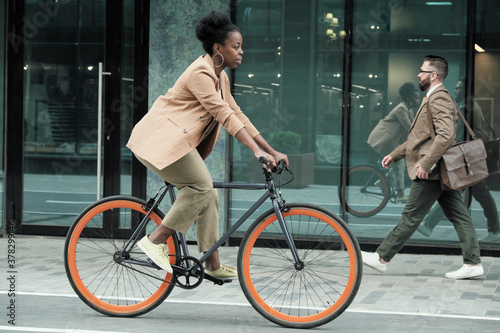 African young woman riding on a bike to her work along the streets in the city