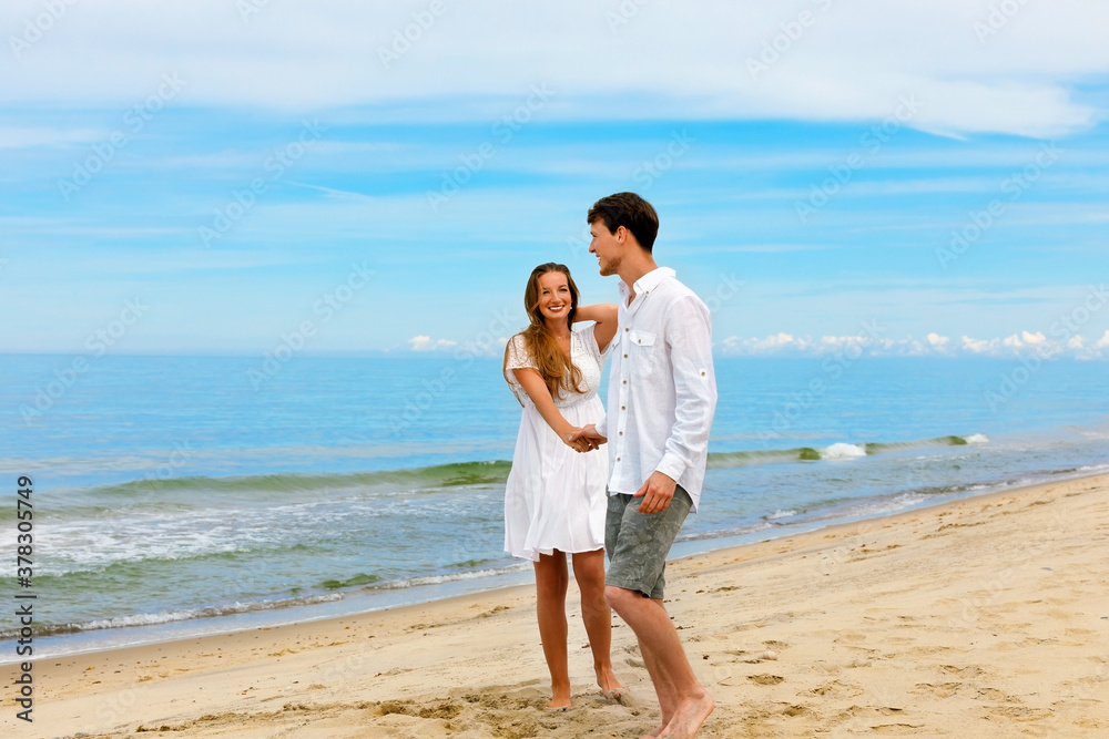 Cute couple of young people in love standing on the sea beach