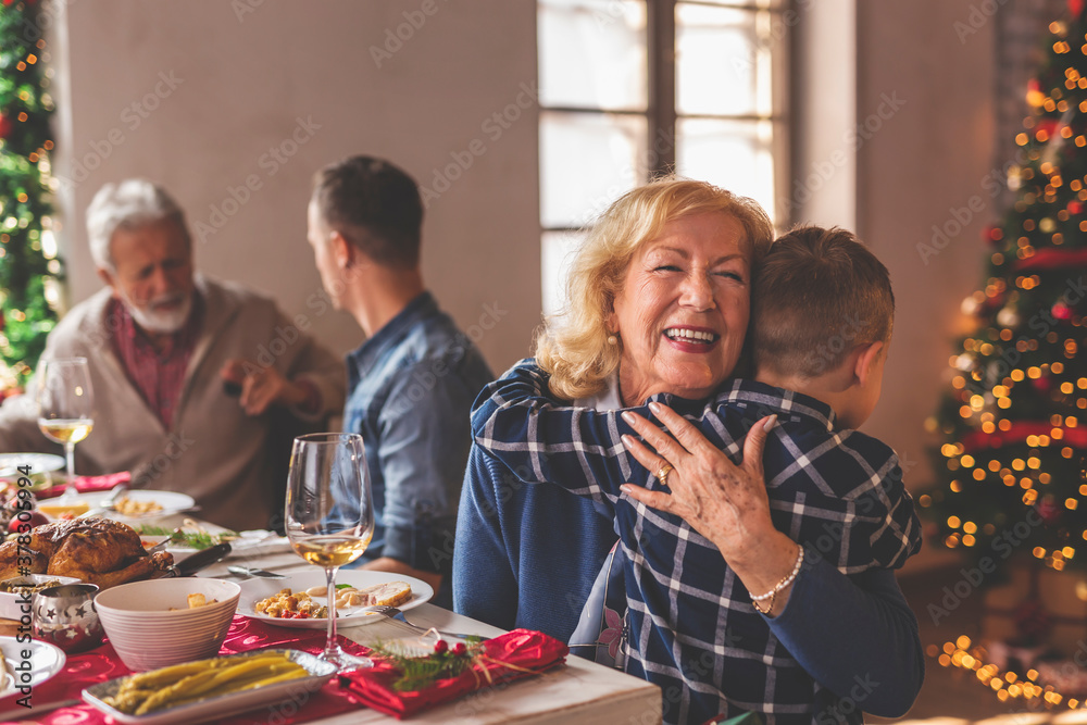 Grandmother hugging grandson while having Christmas dinner Grandmother hugging grandson while having Christmas dinner