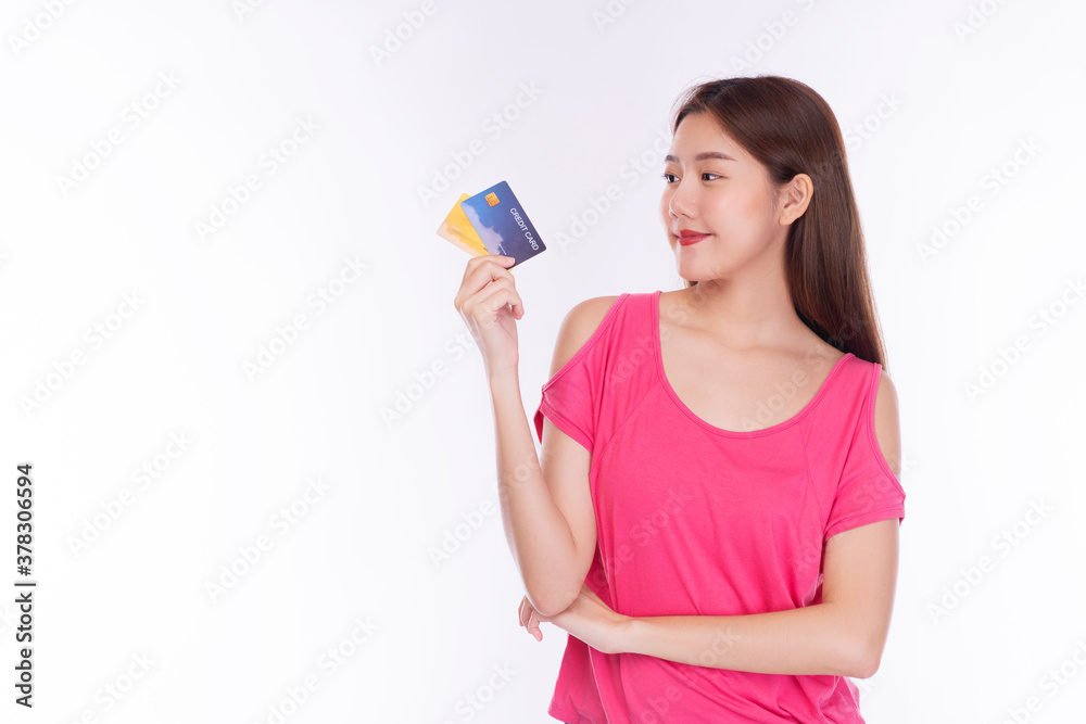 Cheerful young woman wearing casual clothes smiling while holding and looking at credit card mockup over isolated white background. Purchase payment and financial concept. Cheerful young woman wearing casual clothes smiling while holding and looking at credit card mockup over isolated white background. Purchase payment and financial concept.
