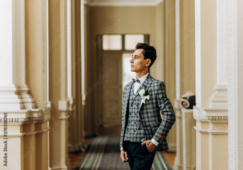 A handsome guy in a fashionable suit is standing in the hallway. A handsome guy in a fashionable suit is standing in the hallway.