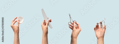 Female hands holding manicure and pedicure tools isolated on blue background with copy space, horizontal banner format. Cotton pads, nail file, scissors and cuticle nippers in human hand photo