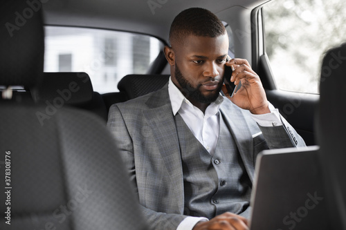 Concentrated black businessman talking on phone in car