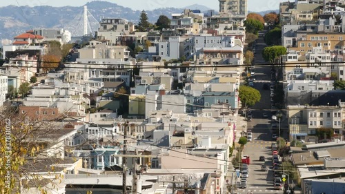 Iconic hilly street and crossroads in San Francisco, Northern California, USA. Steep downhill road and pedestrian walkway. Downtown real estate, victorian townhouses abd other residential buildings.