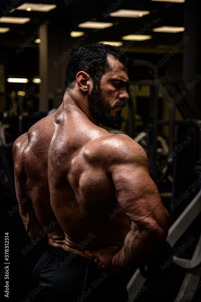 healthy lifestyle of handsome strong young man with beard showing muscle of his mighty sweaty back in dark sport gym healthy lifestyle of handsome strong young man with beard showing muscle of his mighty sweaty back in dark sport gym