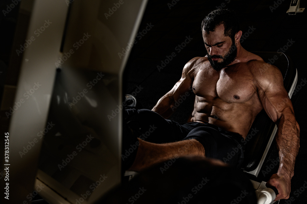 heavy weight workout of bearded strong man in fitness equipment during leg press training heavy weight workout of bearded strong man in fitness equipment during leg press training