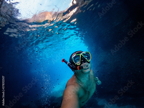 Foto Man diver swimming under the arch of Cala Goloritze in the Gulf of Orosei