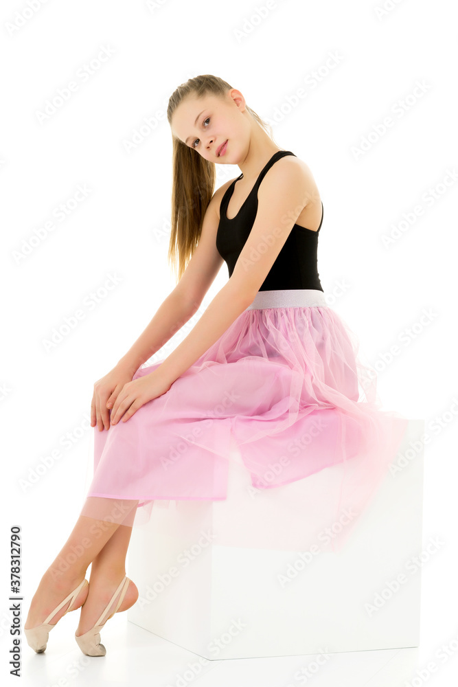 Portrait of a cute girl sitting on a white cube hands on her knees.