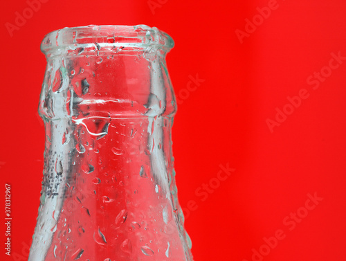 Glass Bottle with Water Droplets on a Red Background