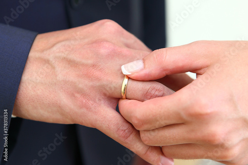 Newlyweds exchange wedding rings. Male and female hand with a ring.