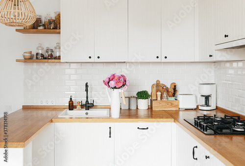 View on clean white simple modern kitchen in scandinavian style  aster Michaelmas daisy bouquet in vase on the table
