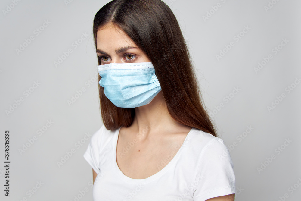 Brunette medical mask looks to the side of a white T-shirt Brunette medical mask looks to the side of a white T-shirt