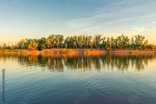 Picturesque summer landscape with riverbank at sunset. Calm plain river, reflection in water. Wonderful nature, beautiful natural background. Akhtuba river, Astrakhan region, Russia photo