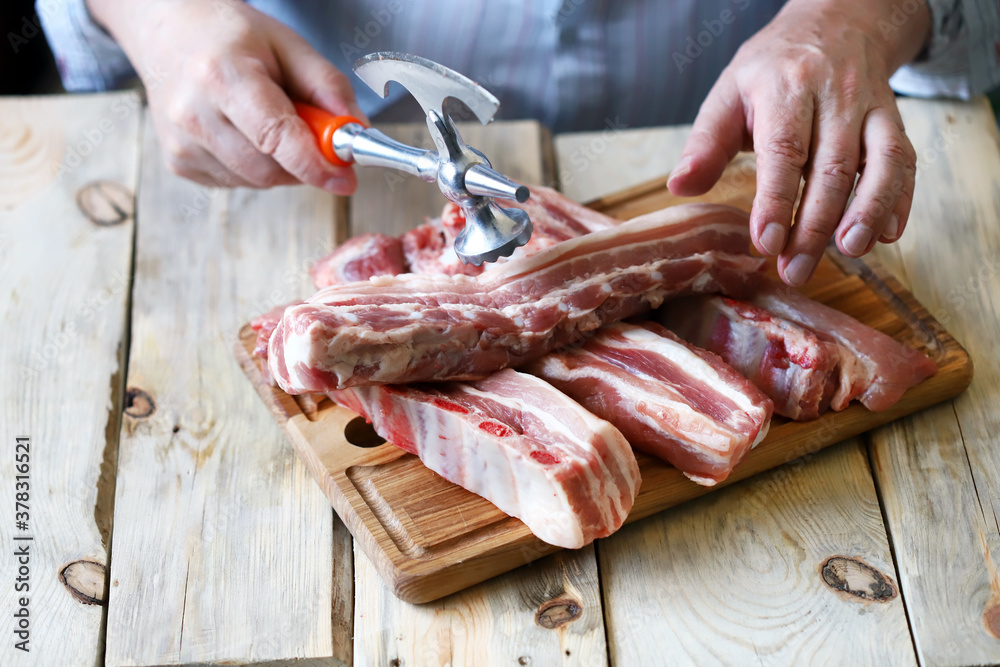 The chef cuts raw pork ribs with a hatchet. Cooking meat. Selective focus. Macro.