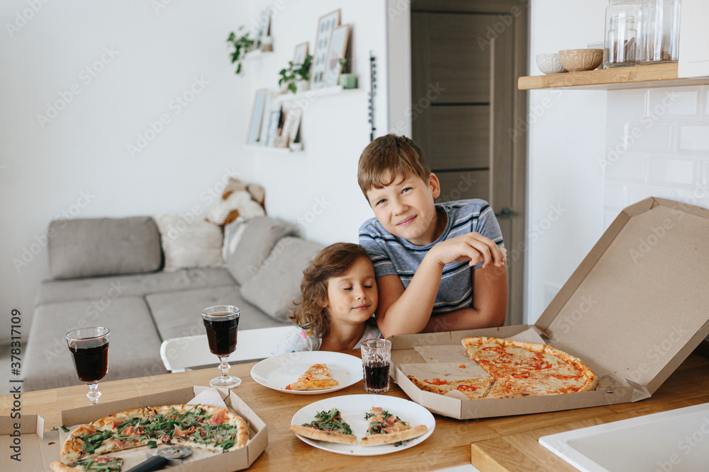 Happy time of eating concept. Kids boy and girl eating pizza at home.