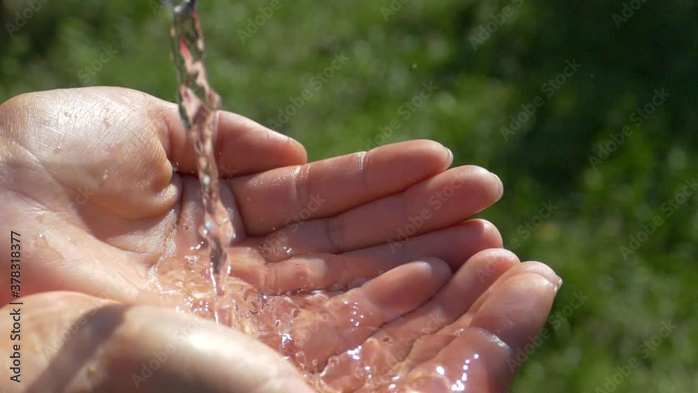 Water flows in a stream into the palms of the hands. Pure water from nature