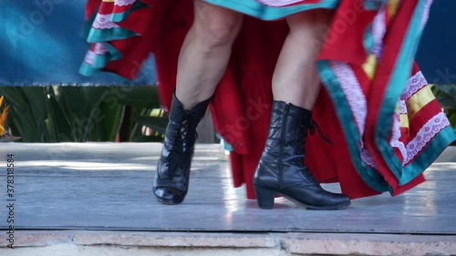 Latino women in colourful traditional dresses dancing Jarabe tapatio, mexican national folk hat dance. Street performance of female hispanic ballet in multi colored ethnic skirts. Girls in costumes.