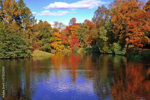 ake in the autumn park, trees are dressed in autumn clothes and are reflected in the water. horizontal photo.