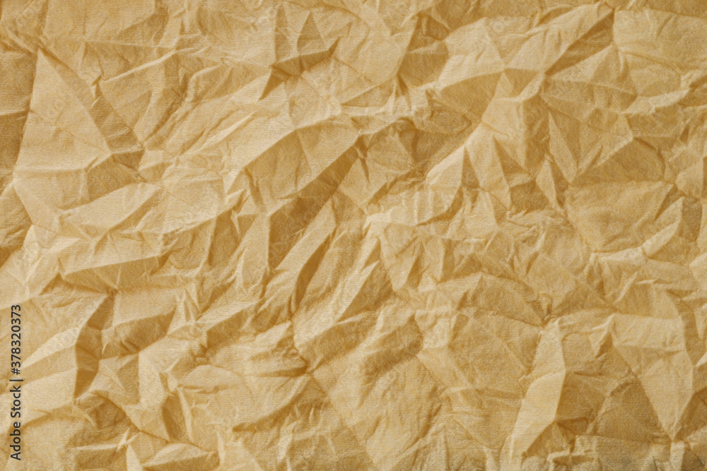 Fototapeta premium The texture of a crumpled yellow-gold disposable textile napkin.