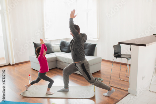 Fotografia Little girl and her young father are doing lunge forward workout at home