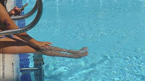Girl With Smartphone Touches Pool Water