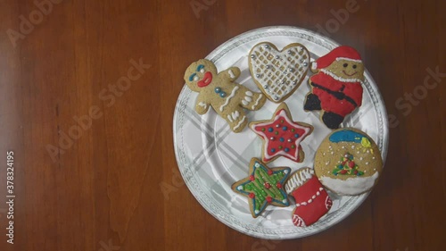 Porcelain plate full of ginger cookies on a wooden table. Every one second, one by one, cookies are disappearing. Last cake is a star figure.