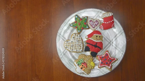 Porcelain plate full of gingerbread cookies on a wooden table. Every one second, one by one, cookies are disappearing. Last cake is a Santa Claus figure.