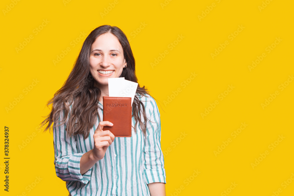 smiling pretty woman looking confident at camera and showing passport with tickets for flight