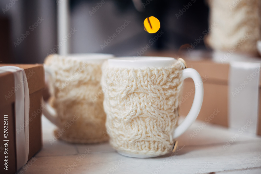 on the table there are two cozy knitted cups with hot cocoa, tea or coffee. Winter and Christmas time concept.