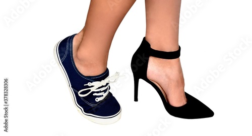 Two different types of shoes: high heels and sneakers on womens feet. Isolated on white background.Concept of females choice of elegance and beauty vs comfort and simplicity.