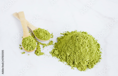 Dried moringa powder in wooden spoons over white background