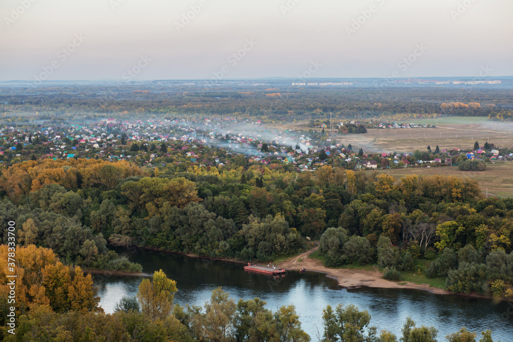 Town in the autumn forest in foggy evening