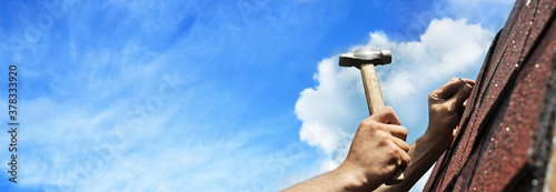 hand with hammer on background of blue sky banner