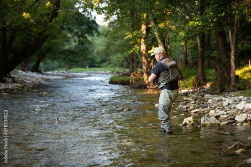 Professional fisherman fly fishing at sunrise on a mountain river.