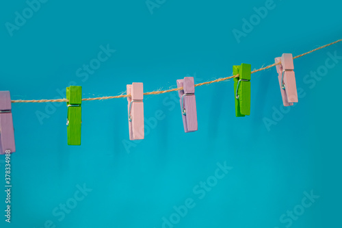 Multicolored wooden clothespins on a rope isolated on blue background