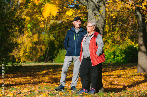 Happy senior couple in love in autumn park. Smiling mature man and old woman having fun outdoors