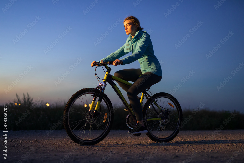 Young woman cycling on bicycle at the night Young woman cycling on bicycle at the night