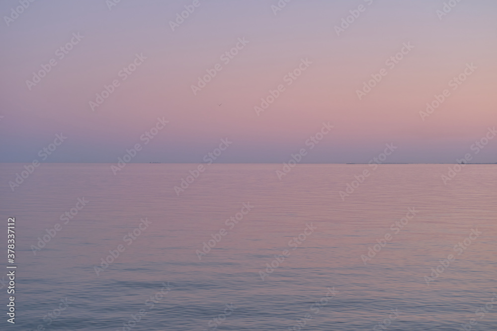 Purple gradient of the sky and sea in the evening. Calm sea wavy surface