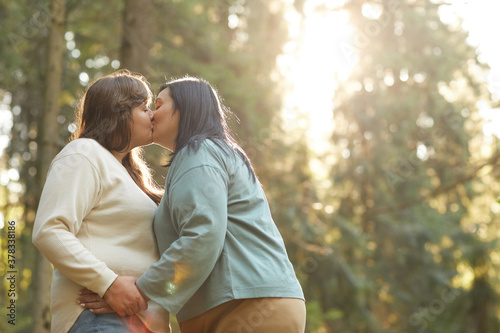 Obraz na plátně Two overweight lesbians kissing each other during their walk in the forest