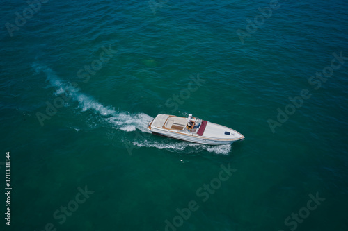 Aerial bird's eye view photo taken by drone of boat. Top view of a white boat sailing to the blue sea.  Motor boat in the sea.Travel - image. © Berg