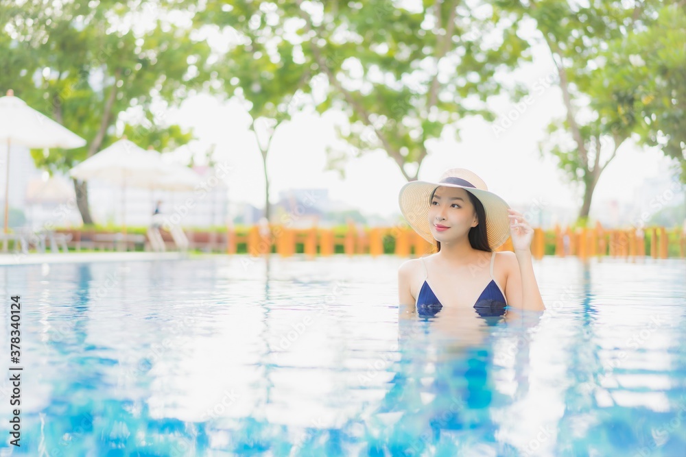 Portrait beautiful young asian woman relax smile around outdoor swimming pool in hotel resort