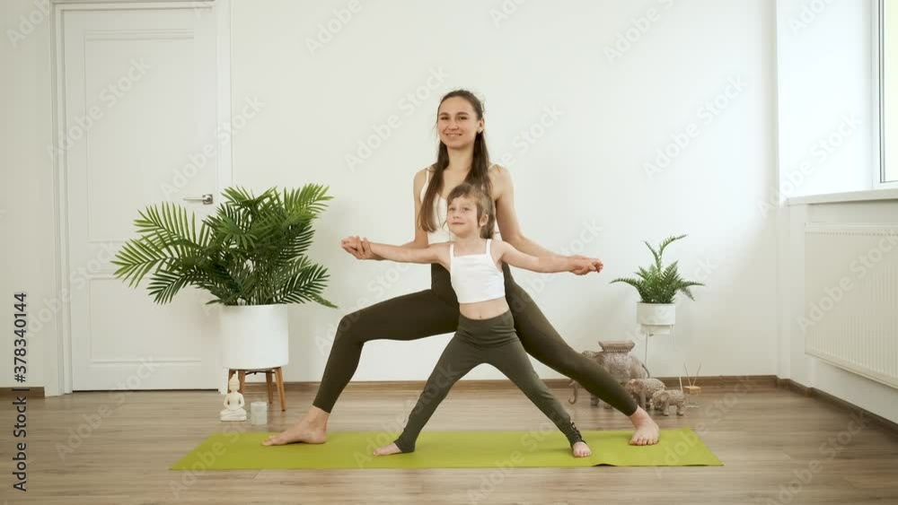 A mother and her 5-year-old daughter practice yoga at home. Meditation and health A mother and her 5-year-old daughter practice yoga at home. Meditation and health