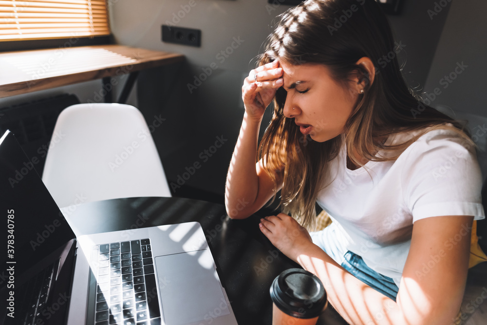 Young frustrated woman working at office desk in front of laptop, suffering from chronic daily headaches, online treatment, medical consultation appointment.