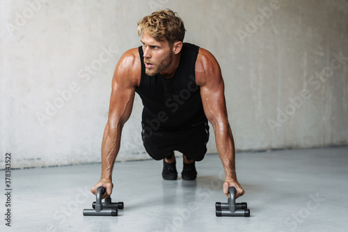 Photo of athletic young sportsman working out with push-up stops photo