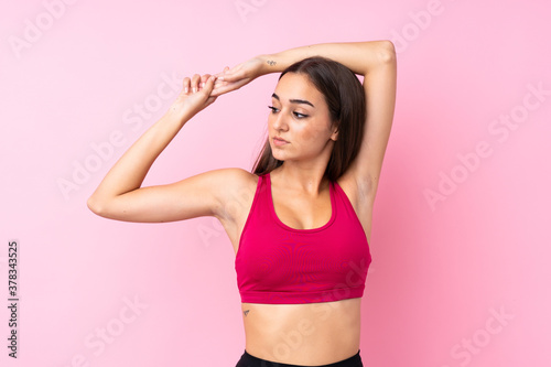 Young sport girl over isolated pink background stretching