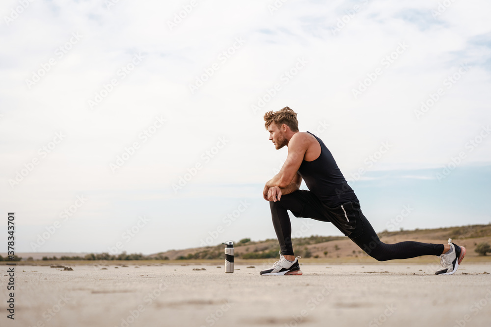 Photo of athletic young sportsman doing exercise while working out